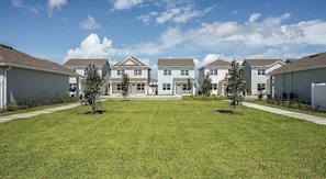 A row of townhouses with a well-maintained lawn and small trees. - Landing | Incredible 3BD, Gym, Yoga Studio (Four Corners)