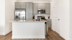 A modern kitchen with grey cabinets, stainless steel appliances, and a marble countertop. - Landing | Incredible 2BD, Yoga Studio, Gym (Four Corners)