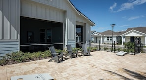 A building with a covered patio area featuring outdoor seating and a brick floor. - Landing | Incredible 2BD, Yoga Studio, Gym (Four Corners)