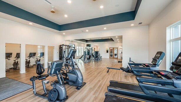 Ein geräumiges Fitnessstudio mit verschiedenen Cardiogeräten und Krafttrainingsgeräten, darunter Laufbänder und Gewichtsmaschinen.