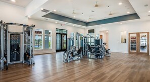 A spacious gym with various exercise machines, large windows, and a wooden floor. - Landing | Incredible 2BD, Yoga Studio, Gym (Four Corners)