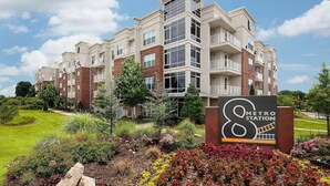 A multi-story apartment building with a sign indicating a metro station nearby. - Landing | Incredible 1BD, Gym, Clubhouse (Charlotte)