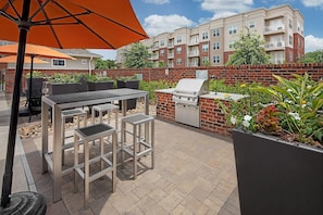 An outdoor patio area with a grill, dining table, and chairs. - Landing | Amazing 1BD, Clubhouse, Gym (Charlotte)