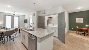 A modern kitchen with granite countertops, stainless steel appliances, and a dining area with a table and chairs. - Landing | Amazing 1BD, Clubhouse, Gym (Charlotte)