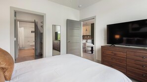 Ein Schlafzimmer mit Bett, Fernseher, Kommode und Spiegel.