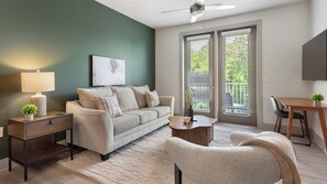 Ein Wohnzimmer mit einer Couch, einem Couchtisch, einem Beistelltisch mit Lampe und einem Fernseher.