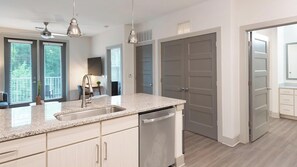 A modern kitchen with a granite countertop, stainless steel appliances, and a dining area visible through an open door. - Landing | Spectacular 1BD, Gym, Clubhouse (Charlotte)