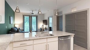 A modern kitchen with granite countertops, stainless steel appliances, and pendant lighting. - Landing | Chic 1BD, Gym, Yoga Studio (Charlotte)