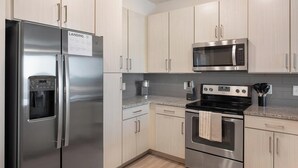 Una cocina moderna con electrodomésticos de acero inoxidable, incluyendo un refrigerador, microondas y horno.