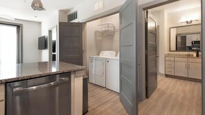 Una cocina moderna con electrodomésticos de acero inoxidable, encimera de granito y zona de lavandería con lavadora y secadora.