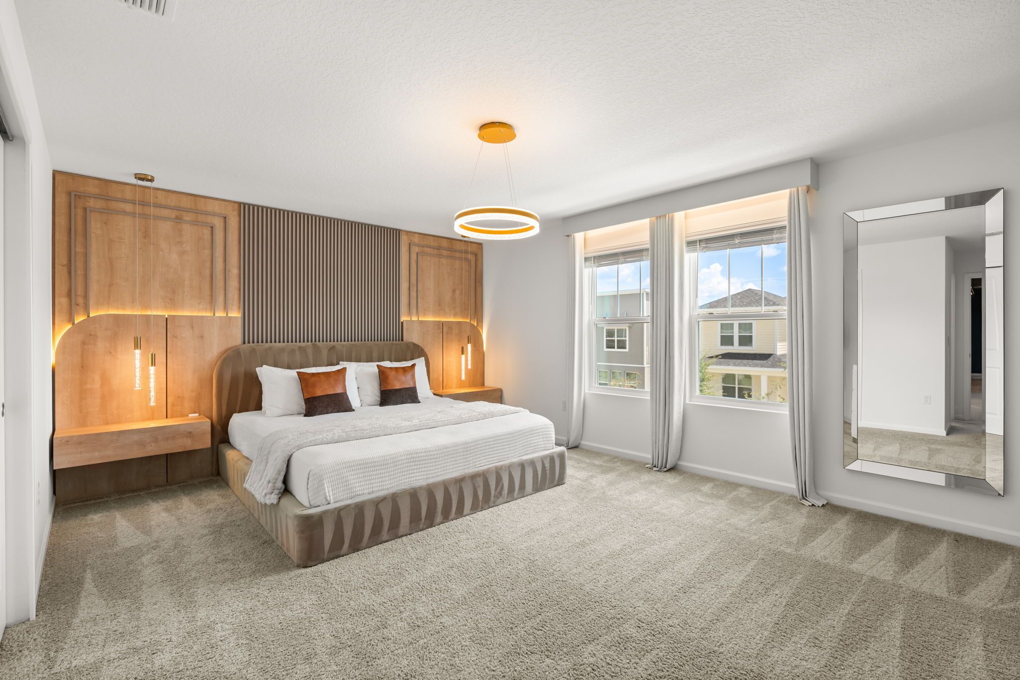 A bedroom with a bed, bedside tables, a wall-mounted light fixture, and a large window.