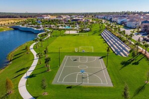 Vue aérienne d’un quartier résidentiel avec un terrain de basketball, un sentier pédestre et des maisons.