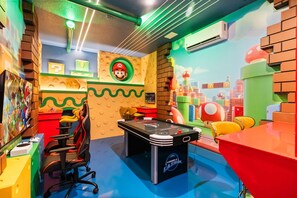 Ein Zimmer mit Poolbillard, Spielsitzgelegenheiten und einer Wand im Mario-Design.