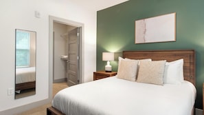 Ein Hotelzimmer mit einem Bett, einem Nachttisch mit Lampe, einer Tür zu einem Schrank und einem gerahmten Bild an der Wand.