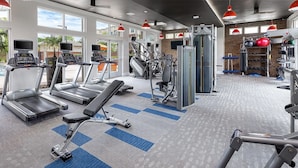 Une salle de sport équipée de tapis de course, d’appareils de musculation et d’une zone dédiée aux exercices de développé couché.