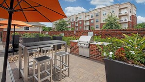Un espace extérieur aménagé avec un barbecue, une table à manger et des chaises.