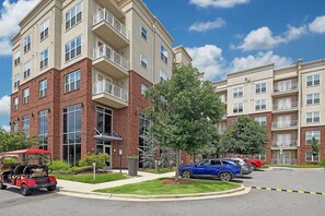 A multi-story apartment building with a brick facade, large windows, and balconies. - Landing | Spectacular 2BD, Yoga Studio, Clubhouse (Charlotte)