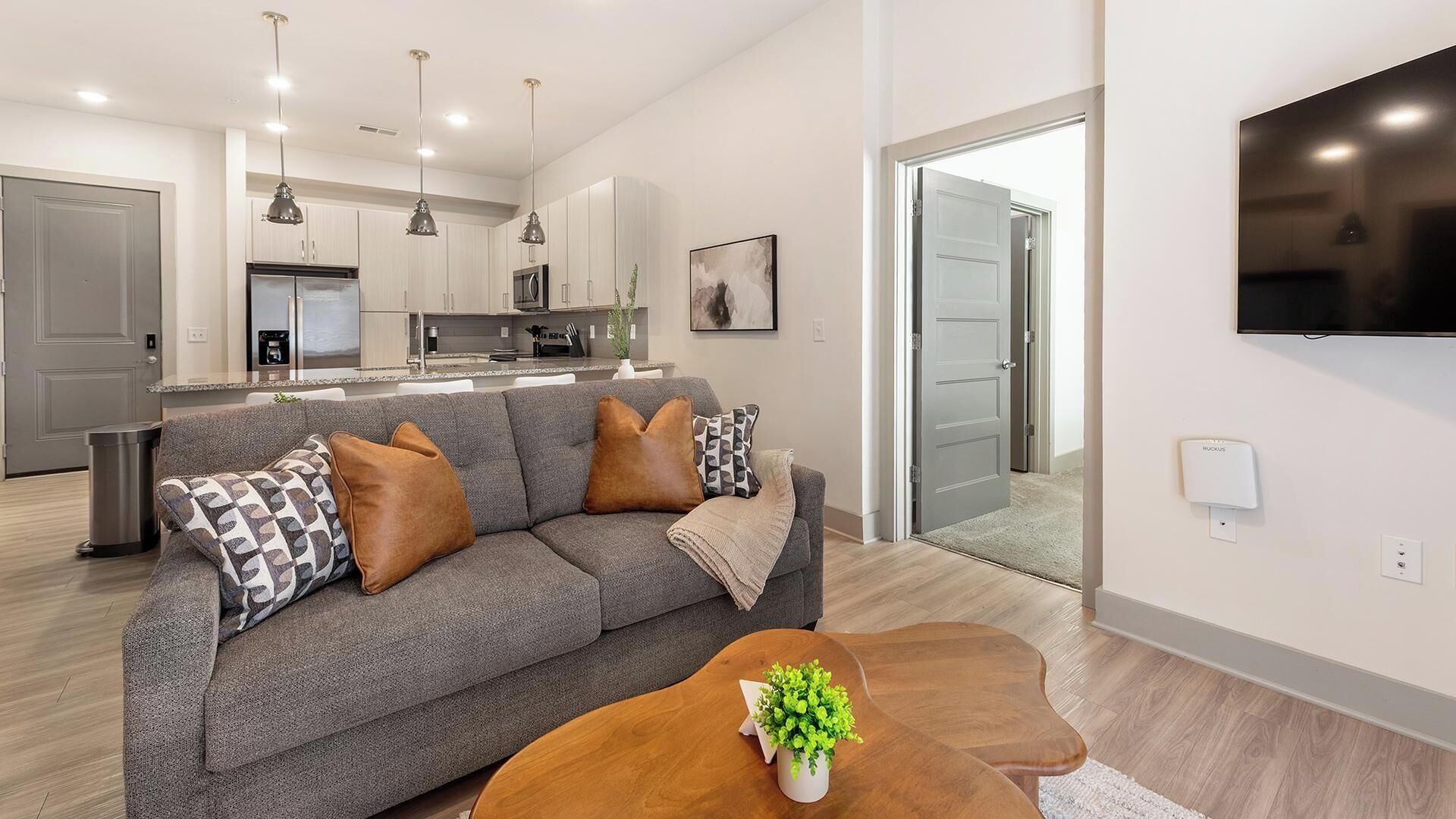 A modern living room with a grey sofa, a coffee table, and a TV mounted on the wall.