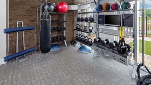 A gym with a brick wall, various exercise equipment, and a TV screen. - Landing | Spectacular 2BD, Yoga Studio, Clubhouse (Charlotte)