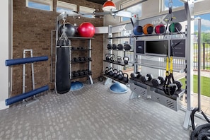 A gym with a brick wall, various exercise equipment, and a TV screen. - Landing | Spectacular 2BD, Yoga Studio, Clubhouse (Charlotte)