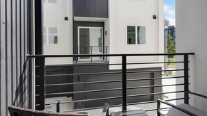 Un edificio moderno con balcón, escalera y vistas del entorno.