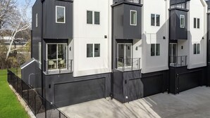 A modern multi-story residential building with a flat roof, large windows, and a gated driveway. - Landing | Spectacular 3BD in Dallas (Dallas)