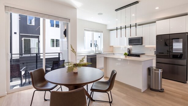A modern kitchen with a central island, stainless steel appliances, and a dining area with a round table and chairs. - Landing | Spectacular 3BD in Dallas (Dallas)