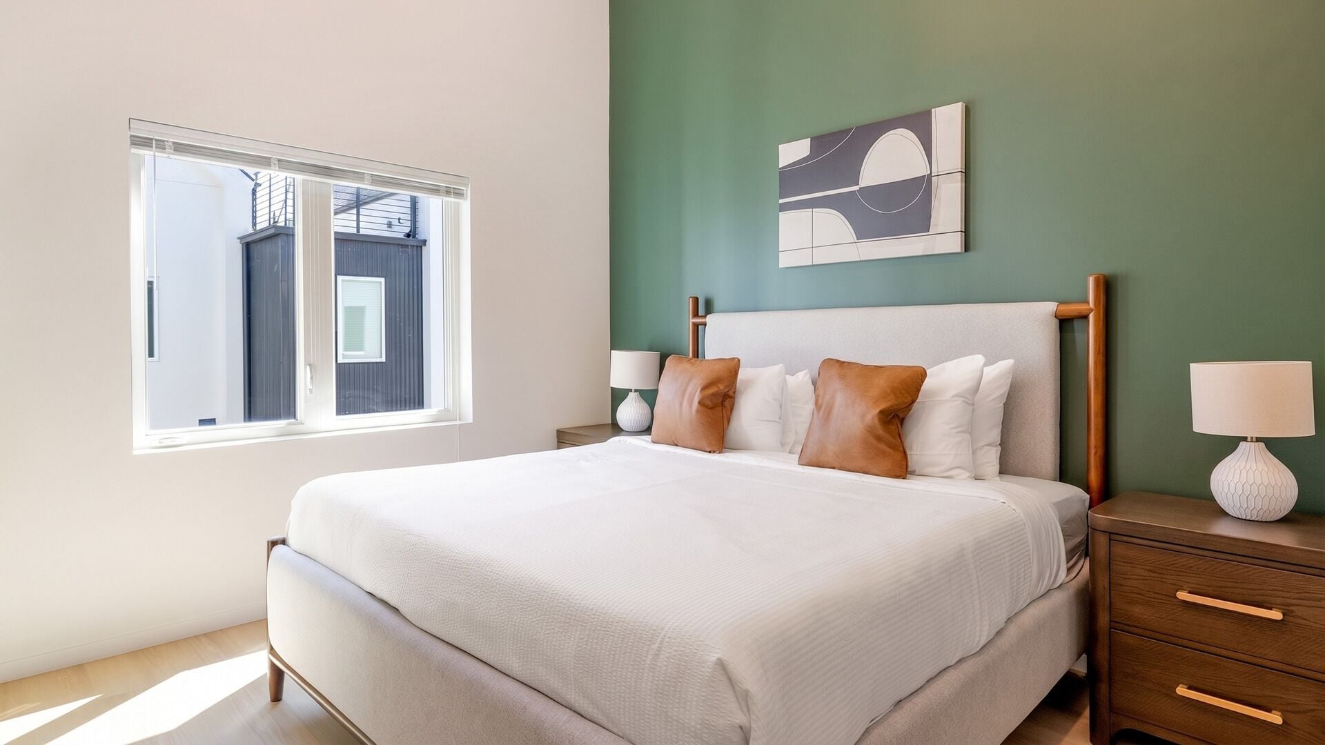 Ein Schlafzimmer mit einem Bett, Nachttischen, einem Fenster und Kunstwerken an der Wand.