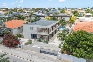 A modern two-story house with a flat roof, a balcony, and a swimming pool.