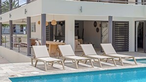 Ein Poolbereich mit Liegestühlen und einem Esstisch.