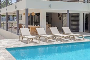 Ein Poolbereich mit Liegestühlen und einem Esstisch.