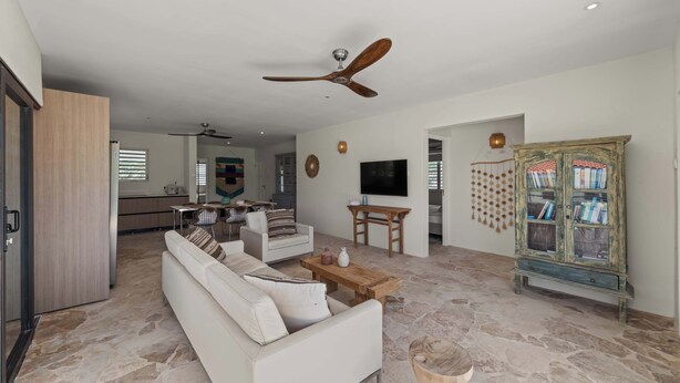 Ein geräumiger Wohnbereich mit Sofa, Couchtisch und Deckenventilator.