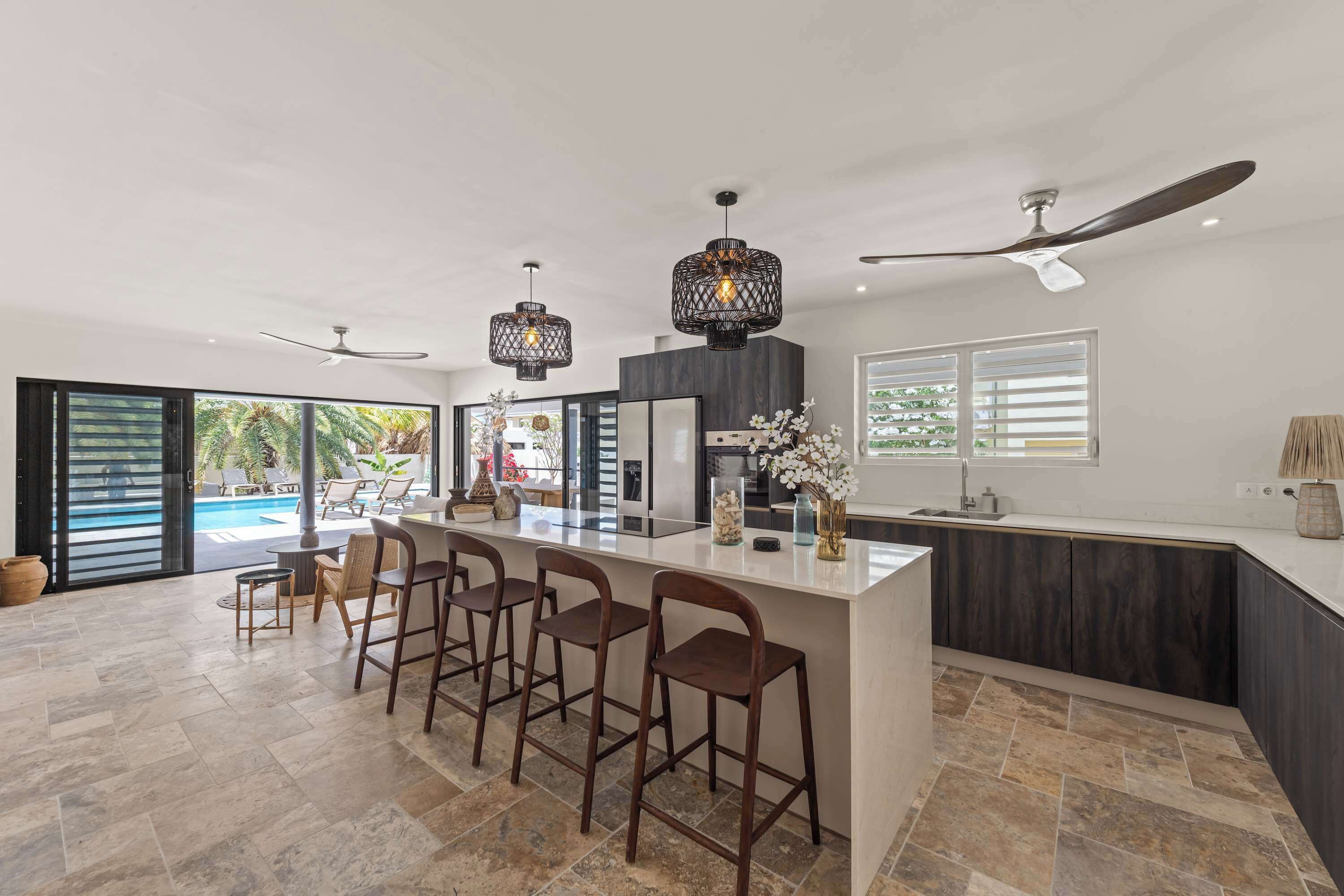 A modern kitchen with a large island, bar stools, and pendant lighting.