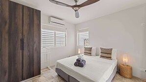 Ein Schlafzimmer mit einem Bett, einem Deckenventilator, einer Klimaanlage und einem Fenster mit Jalousien.