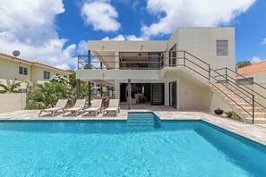 A modern two-story building with a swimming pool, outdoor seating, and a staircase leading to a balcony. - Villa Mira Alma full house Contemporary Luxury Villa in the Heart of Jan Thiel (Jan Thiel)