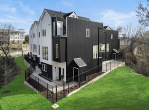 Ein modernes Wohngebäude mit zwei Etagen, flachem Dach, großen Fenstern und einer schwarz-weißen Fassade.