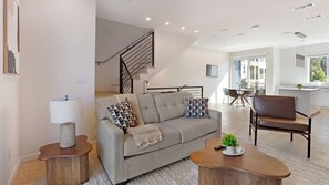 Ein modernes Wohnzimmer mit einer Couch, einem Couchtisch und einer Treppe.