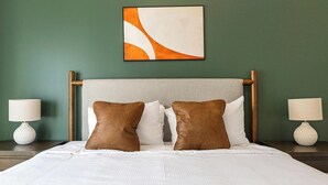 A hotel room with a bed, two nightstands, and a wall-mounted abstract painting. - Landing | Amazing 3BD in Dallas (Dallas)