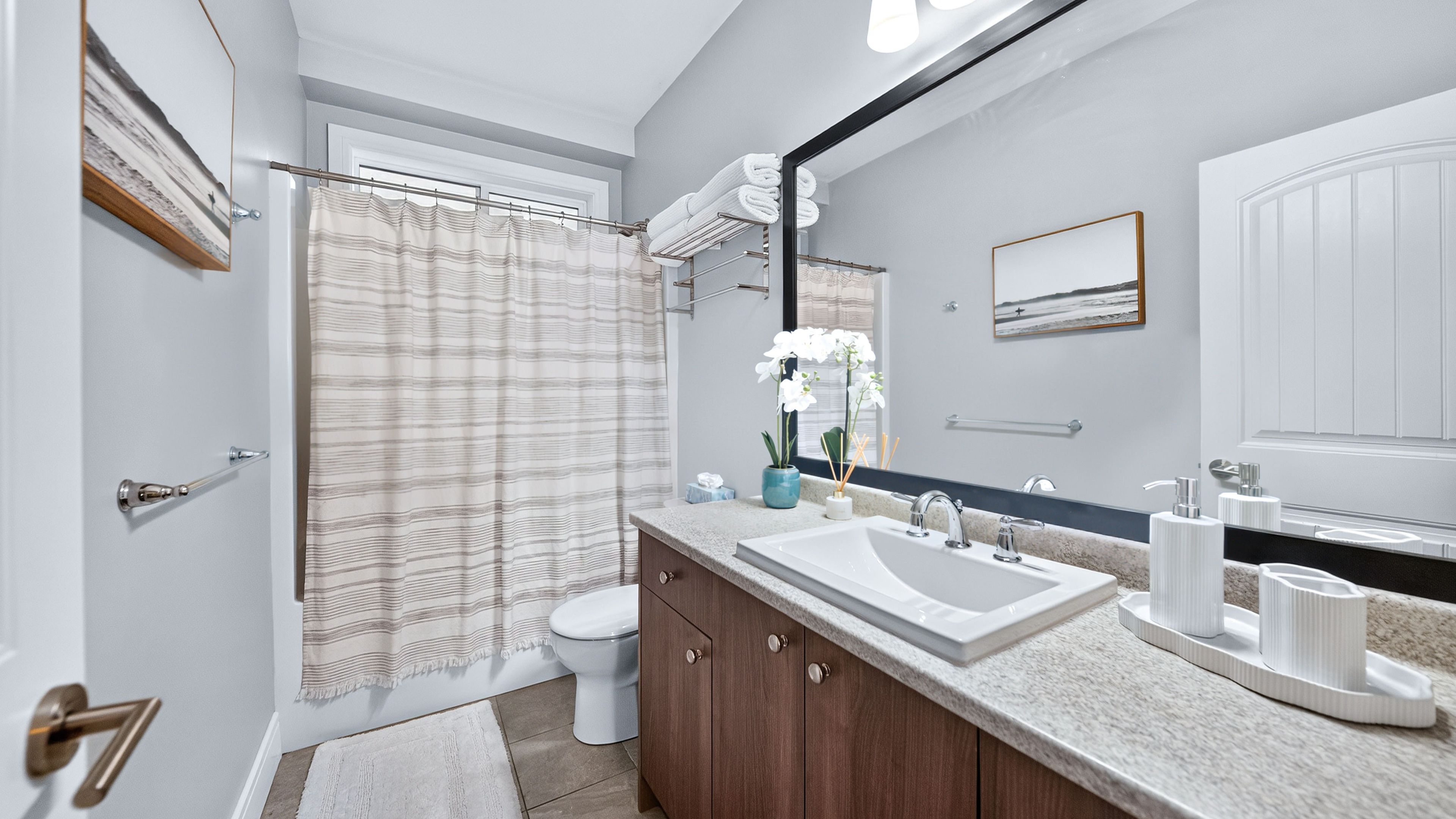 Ein modernes Badezimmer mit Duschvorhang, Toilette, Waschbecken und Waschtisch.