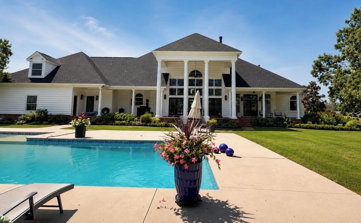Une propriété résidentielle dotée d’une piscine, d’un patio couvert et d’une pelouse bien entretenue.