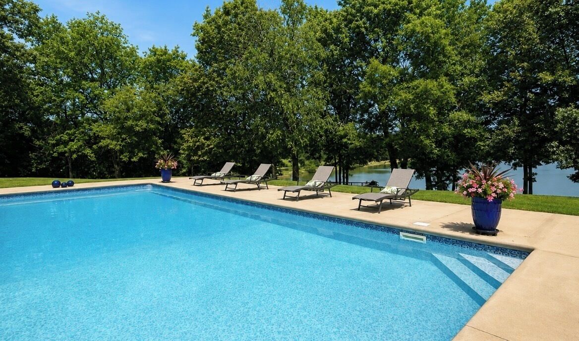 Ein Swimmingpool mit Liegestühlen und Topfpflanzen.