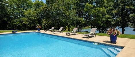 Ein Swimmingpool mit Liegestühlen und Topfpflanzen.