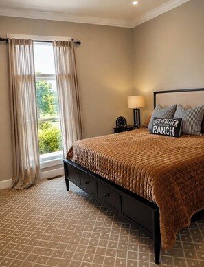 A bedroom with a bed, a nightstand, a lamp, and a view of greenery outside. - Private Luxury Estate-Large Fishing Pond-Pool-Event/Wedding Venue (Benton)