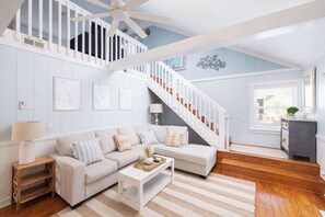 A spacious living room with a white staircase, a sofa set, a coffee table, and a lamp. - Newly Renovated Family Home in Ocean Sands (Corolla)