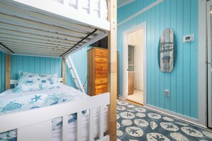 A room with a bunk bed, a dresser, and a door leading to another room. - Newly Renovated Family Home in Ocean Sands (Corolla)