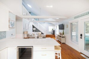 A spacious kitchen with a central island, a dining area with a sofa, and a staircase leading to an upper level. - Newly Renovated Family Home in Ocean Sands (Corolla)