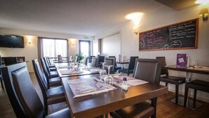 A restaurant with multiple dining tables, chairs, and a menu board on the wall. - Hotel Inn Design Resto Novo Alencon (Valframbert)