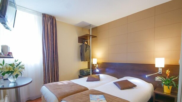 A hotel room with two beds, a small table, a TV, and a window with curtains. - Hotel Inn Design Resto Novo Alencon (Valframbert)