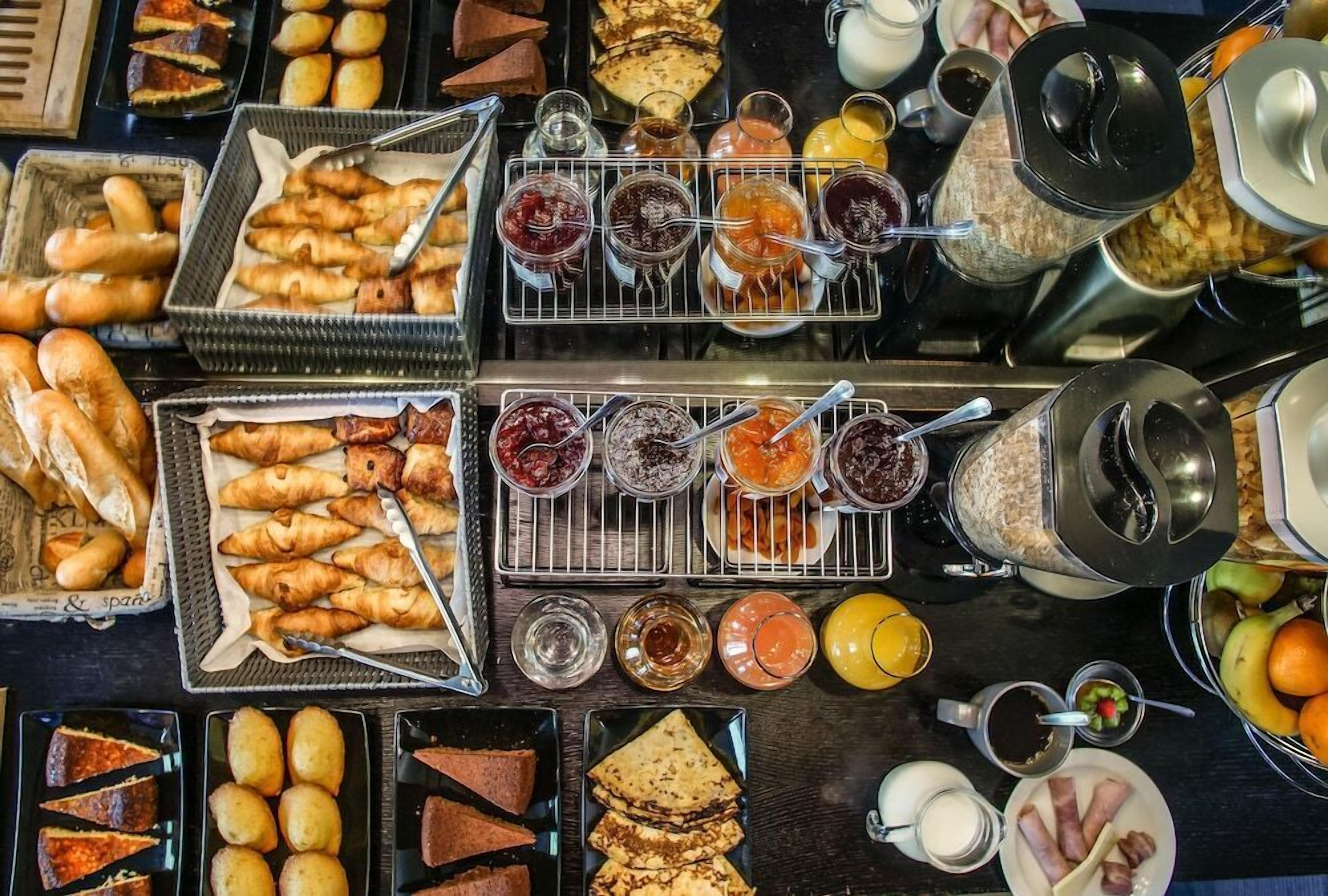 A breakfast buffet with various pastries, sandwiches, and condiments.