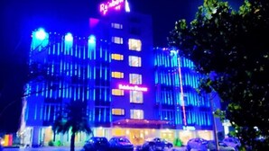 Un immeuble à plusieurs étages, doté d’une enseigne lumineuse, et plus particulièrement d’une grande enseigne « Rainbow Resort » placée en haut.